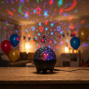 Veilleuse projecteur d'étoiles allumée sur une table lors d'une fête d'anniversaire avec des ballons colorés