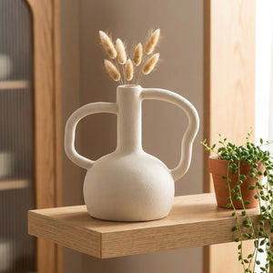 Vase en céramique blanc crème sur une étagère murale près d'une plante