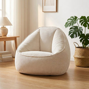 Fauteuil pouf blanc velours côtelé posé près d'une fenêtre lumineuse avec une plante
