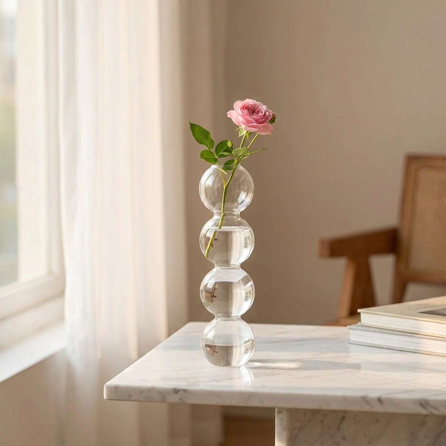 Vase en verre à bulles avec une rose sur une table en marbre près d'une fenêtre