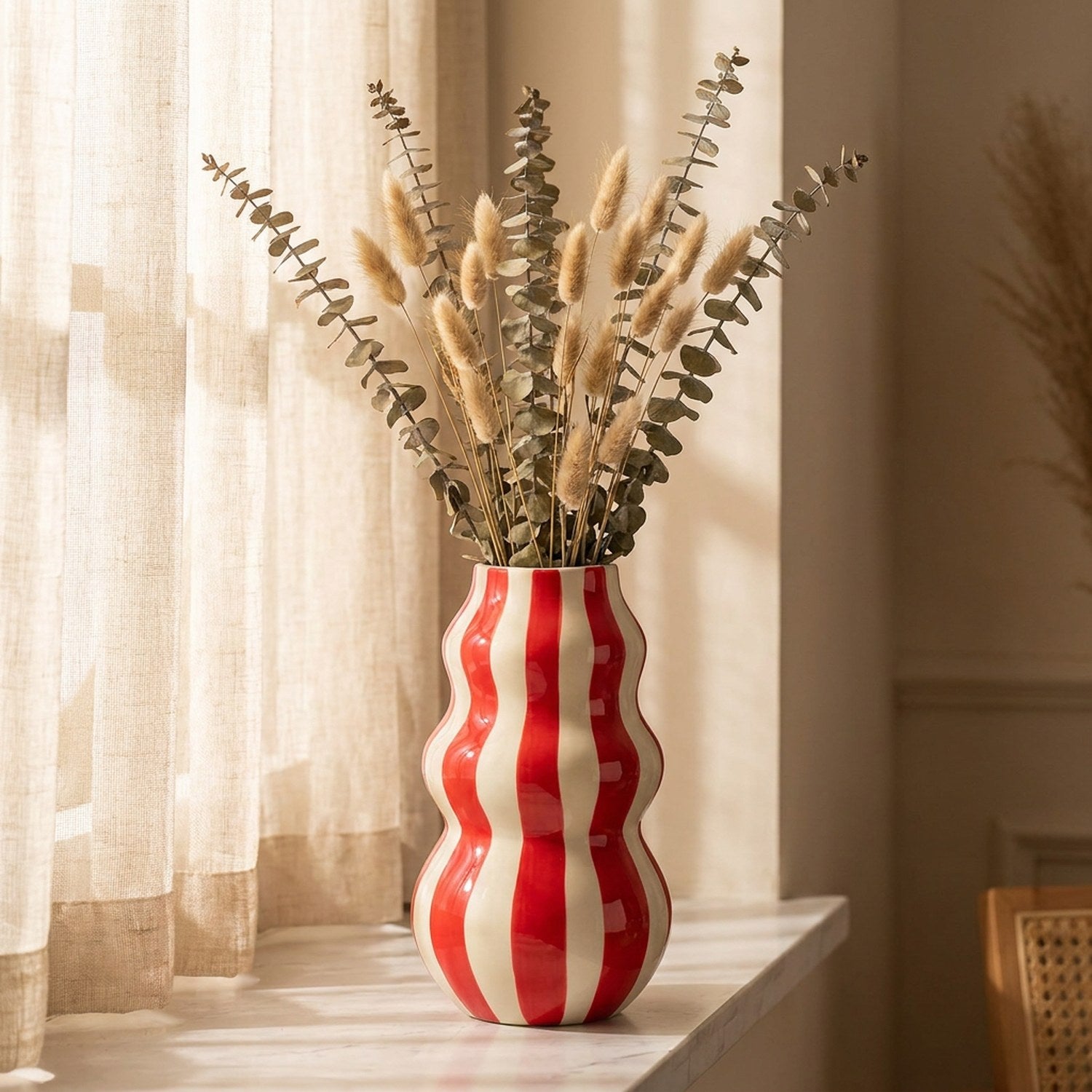 Grand vase rayé rouge aux courbes ondulées avec eucalyptus sur une étagère en marbre