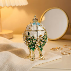 Boîte à bijoux œuf émaillé blanc sur une coiffeuse avec miroir et bijoux dorés