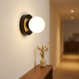 Applique murale noire allumée au dessus d'une console dans un couloir
