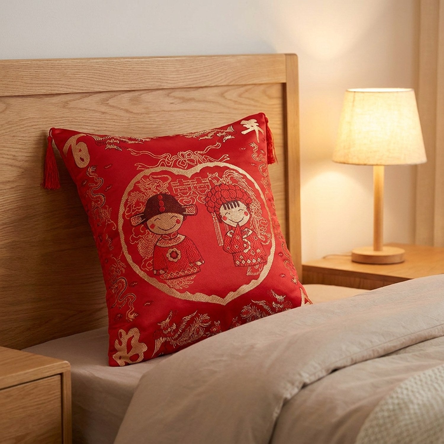 Housse de coussin brodée motif mariés chinois posée sur un lit contre une tête de lit en bois