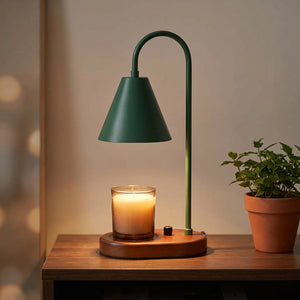 Lampe chauffe-bougie verte avec socle en bois sur une console avec une plante verte