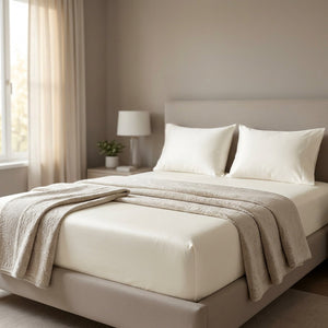 Drap-housse blanc sur un lit dans une chambre élégante façon hôtel avec plaid replié