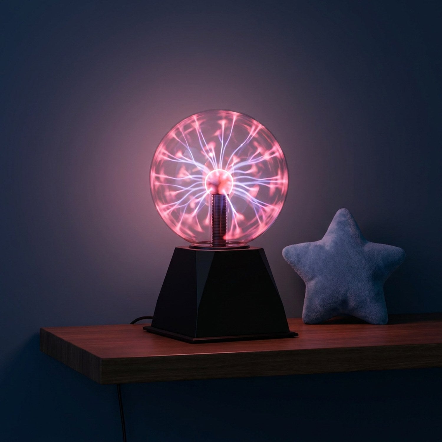 Lampe boule de plasma allumée sur une étagère murale avec un coussin étoile