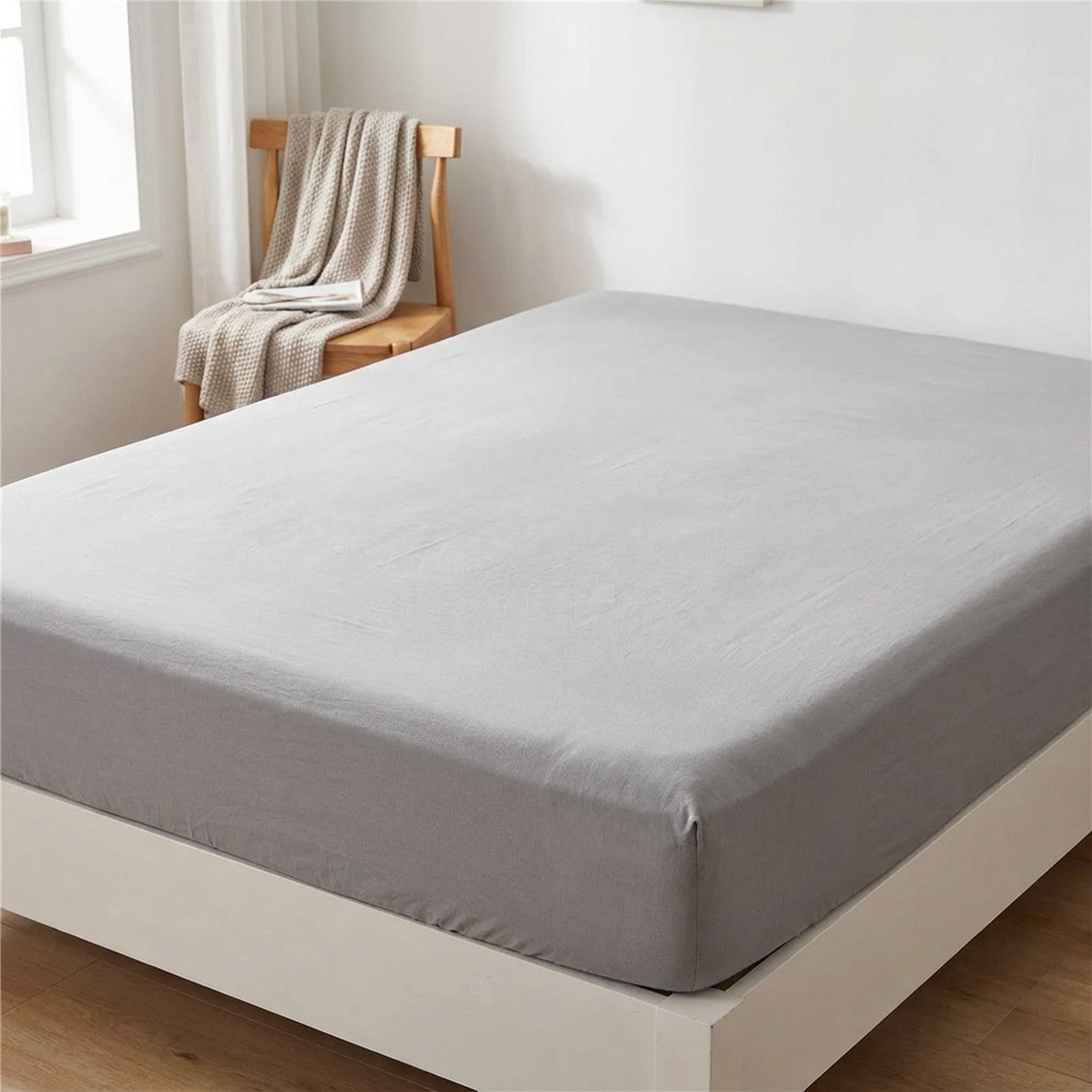 Drap housse gris parfaitement ajuste sur le matelas dans une chambre lumineuse