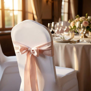 Détail d'une housse de chaise blanche nouée d'un ruban satin rose dans une salle de réception