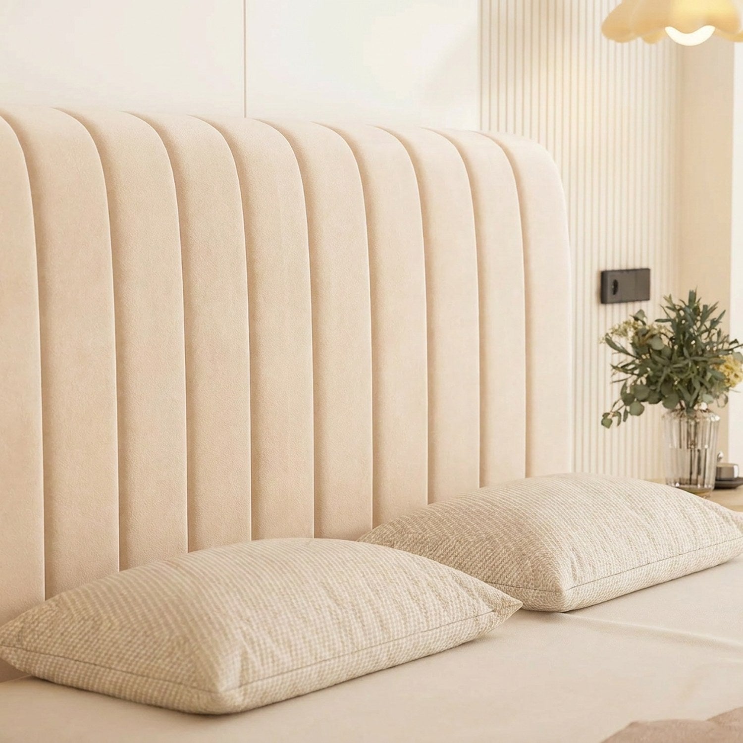 Détail du capitonnage vertical de la housse de tête de lit beige avec oreillers