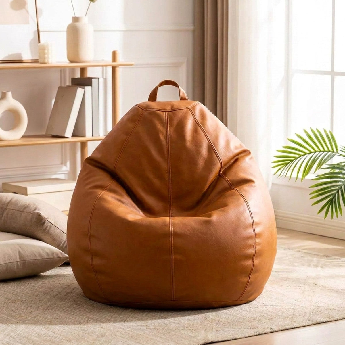 Fauteuil pouf poire simili cuir camel dans un salon lumineux avec étagère et plante