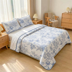 Couvre-lit fleuri bleu et blanc habillant un grand lit dans une chambre moderne