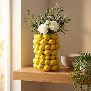 Vase citron en céramique jaune sur une étagère en chêne à côté de bols en grès et d'une plante verte