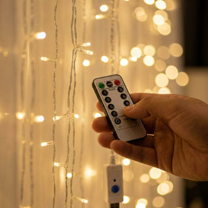 Gros plan sur les perles lumineuses du rideau LED avec télécommande à la main