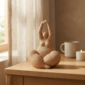 Statue de femme ronde terracotta sur un bureau en bois près d'une fenêtre lumineuse