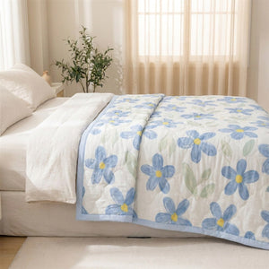 Couette d'été à fleurs bleues sur un lit près d'une fenêtre lumineuse avec plante