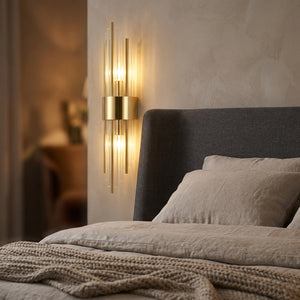 Applique murale dorée allumée au-dessus d'une tête de lit dans une chambre cosy