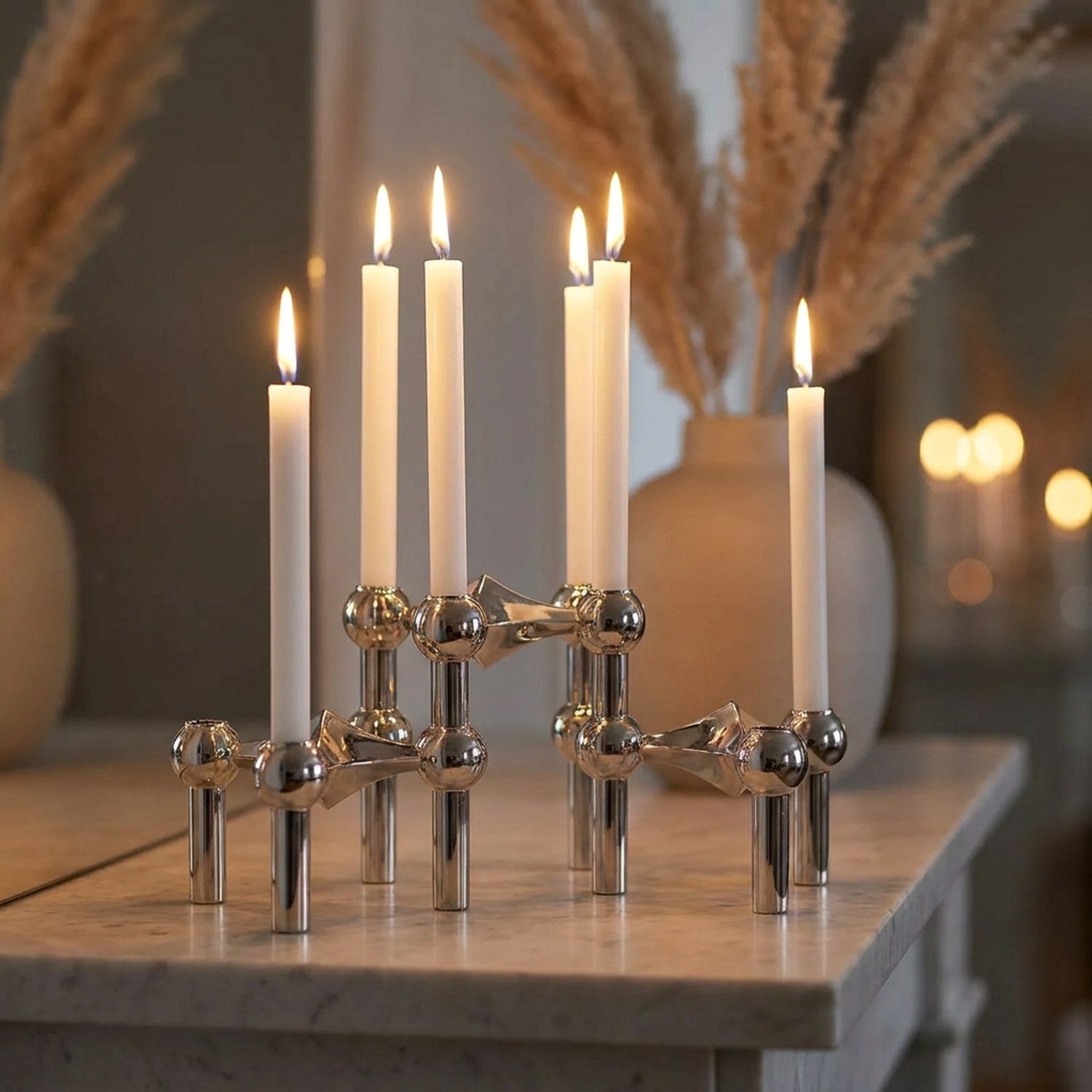 Chandeliers modulaires argentés sur une étagère en marbre avec des herbes de la pampa