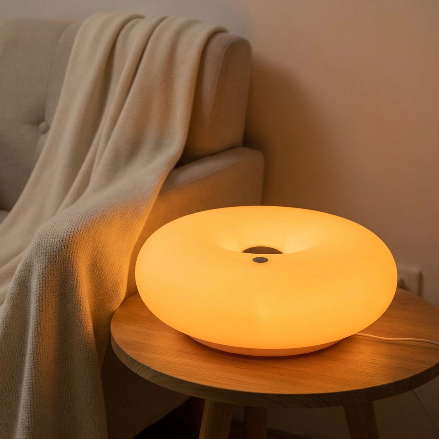 Lampe beignet Bauhaus allumée en orange près d'un fauteuil cocooning