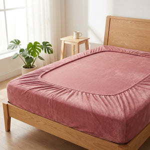 Drap-housse rose posé sur un lit en bois dans une chambre lumineuse et aérée