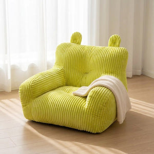 Pouf mini canapé enfant près d'une fenêtre avec un plaid beige posé sur l'accoudoir