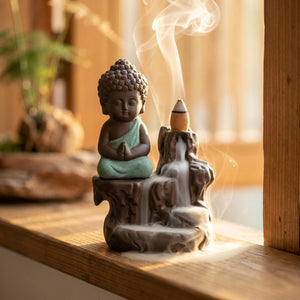 Brûleur d'encens bouddha sur un rebord de fenêtre en bois éclairé par une lumière dorée