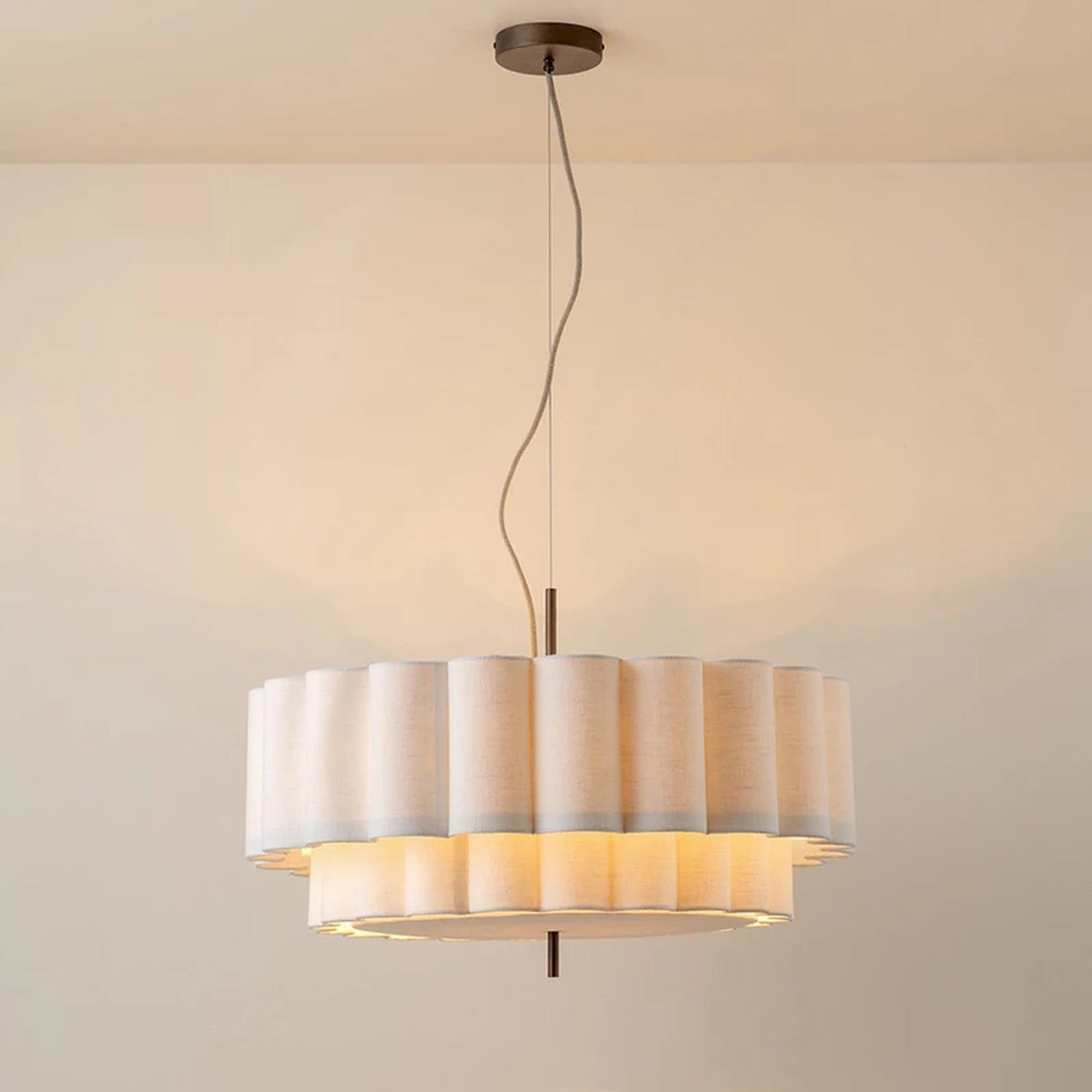 Suspension ronde en tissu beige à deux étages fixée au plafond dans une pièce épurée