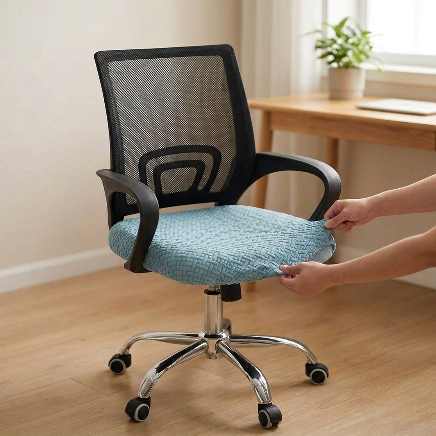 Mains enfilant la housse d'assise extensible bleue sur le coussin d'une chaise de bureau