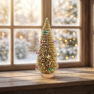 Sapin de Noël miniature doré posé sur un rebord de fenêtre enneigé en hiver