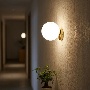 Applique murale boule de verre dorée dans un couloir la nuit
