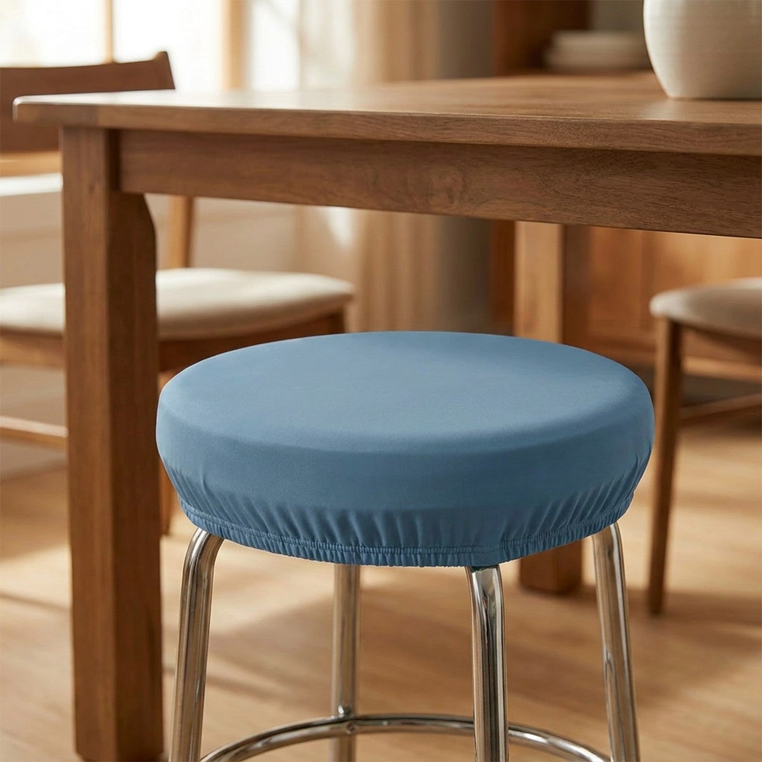Tabouret rond habillé d'une housse bleue sous une table à manger en bois
