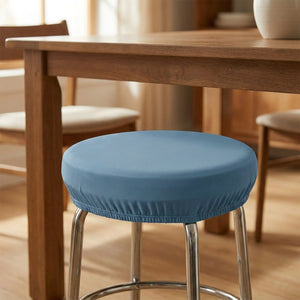 Tabouret rond habillé d'une housse bleue sous une table à manger en bois