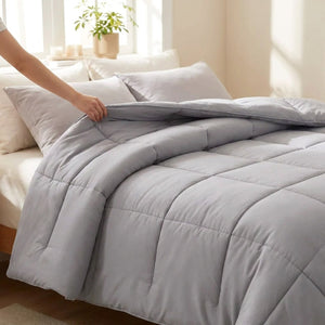 Main ajustant la couette moelleuse grise sur un lit fait