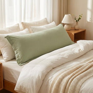 Gros plan sur un long lit habillé d'une taie de traversin verte en microfibre douce