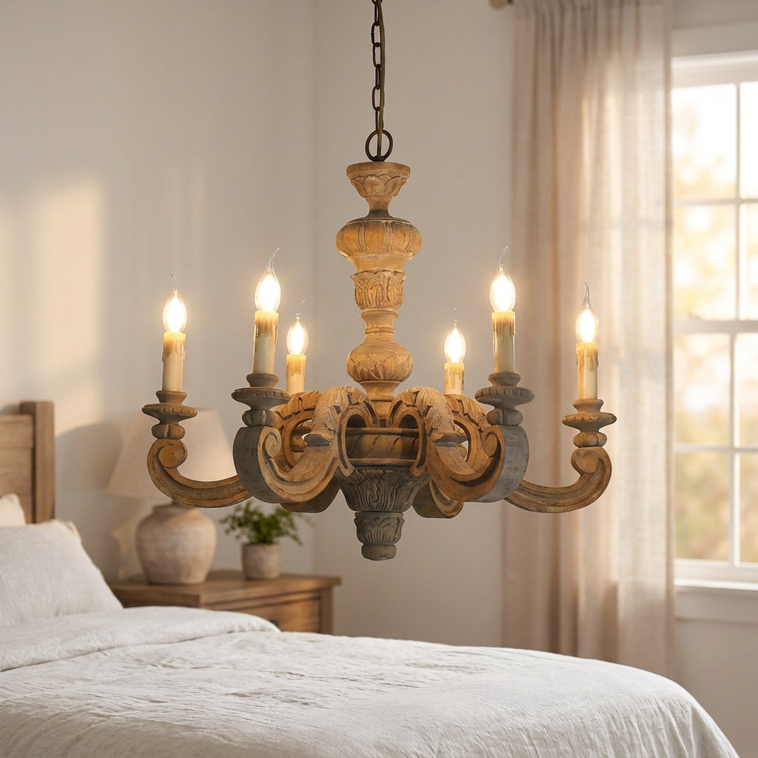 Lustre en bois sculpté éclairé au-dessus d'un lit dans une chambre romantique