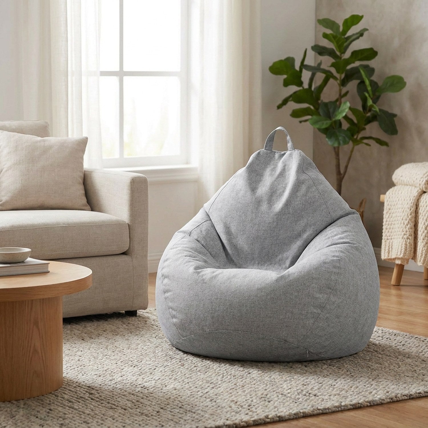 Pouf poire gris installe dans un salon scandinave pres d un canape en lin