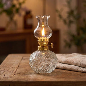 Lampe à huile en verre taillé allumée sur une table de salon avec du linge en lin