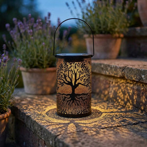 Lanterne solaire arbre de vie posée sur une marche en pierre entourée de pots de lavande