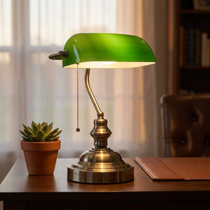 Lampe de bureau verte allumée sur un bureau près d'une plante en pot