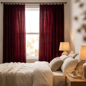 Rideaux en velours bordeaux dans une chambre cosy filtrant la lumière du matin