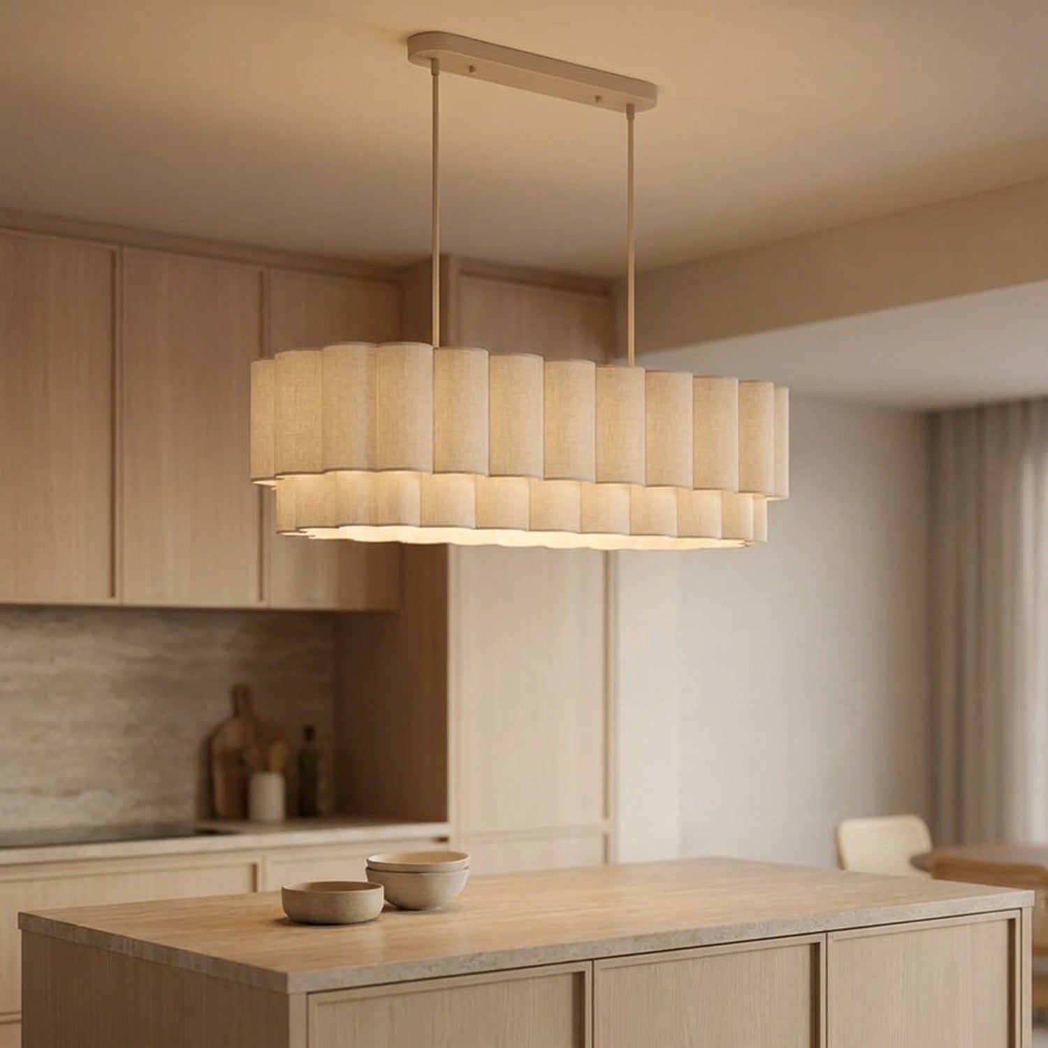 Suspension linéaire en tissu beige allumée au-dessus d'un îlot de cuisine en bois clair