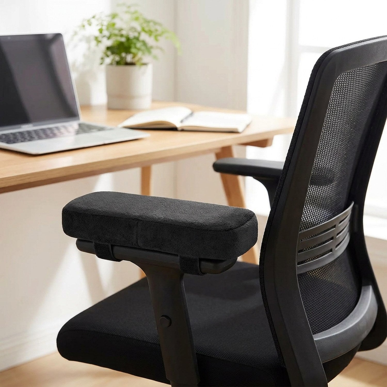 Coussinet d'accoudoir noir sur une chaise de bureau à dossier filet dans un bureau lumineux