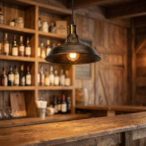 Suspension industrielle bronze allumée au-dessus d'un comptoir de bar