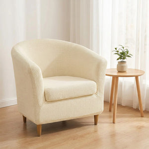 Fauteuil club recouvert d'une housse écru près d'une table d'appoint ronde dans un intérieur clair