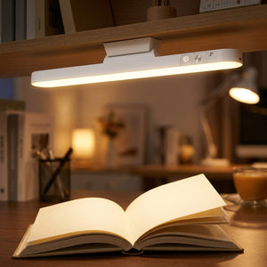 Lampe LED de lecture allumée au-dessus d'un livre ouvert sur un bureau