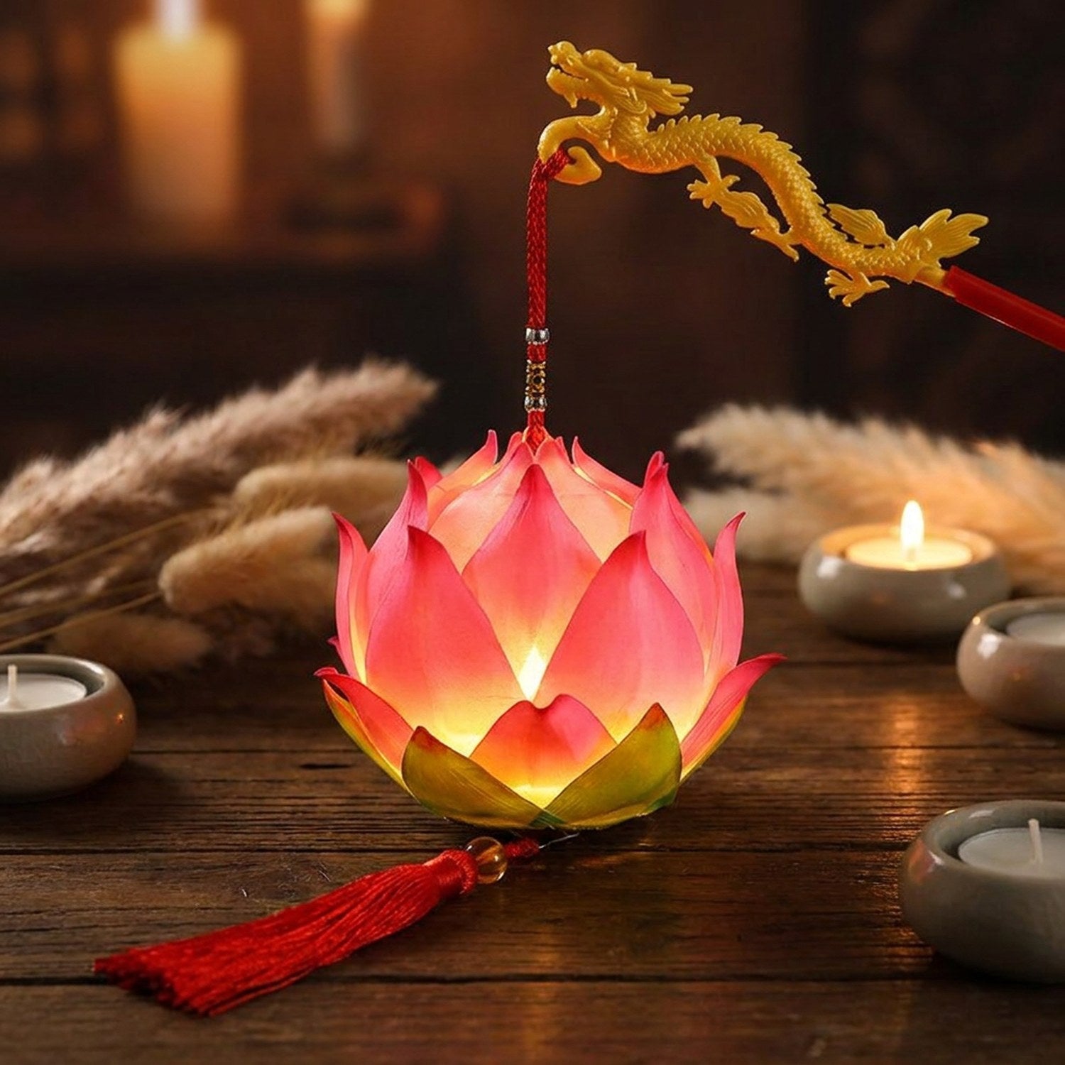 Lanterne lotus rose illuminée sur une table en bois entourée de bougies et de pampa