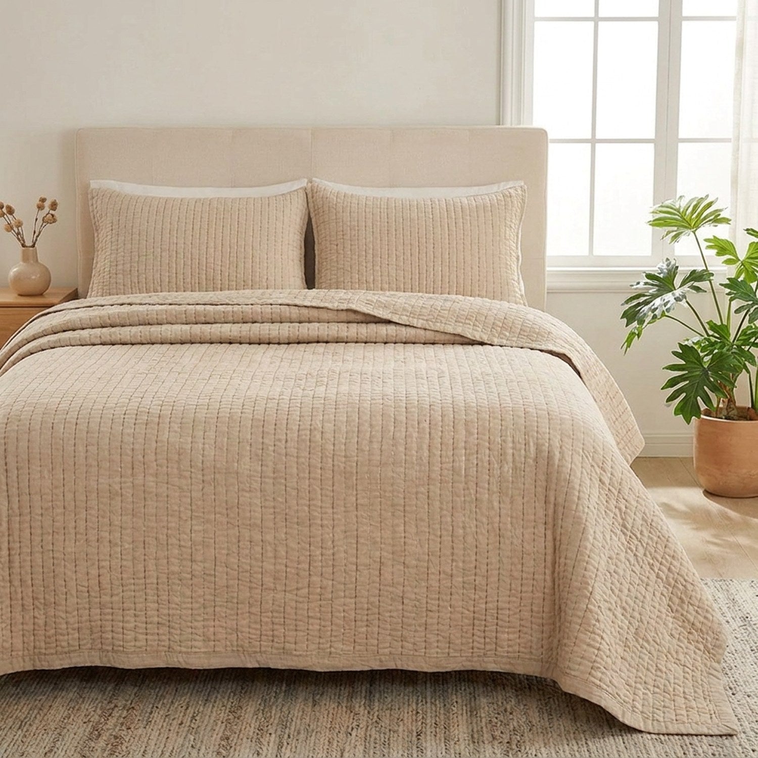 Couvre-lit matelassé beige sur un lit dans une chambre lumineuse avec une plante verte