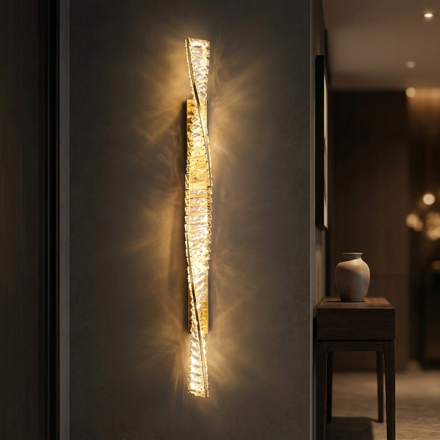 Applique murale dorée en cristal allumée dans une entrée près d'une console