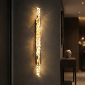 Applique murale dorée en cristal allumée dans une entrée près d'une console
