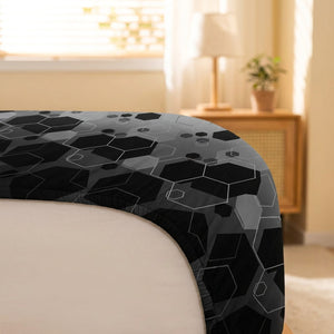 Gros plan sur le coin élastique du drap-housse imprimé hexagones tendu autour du matelas